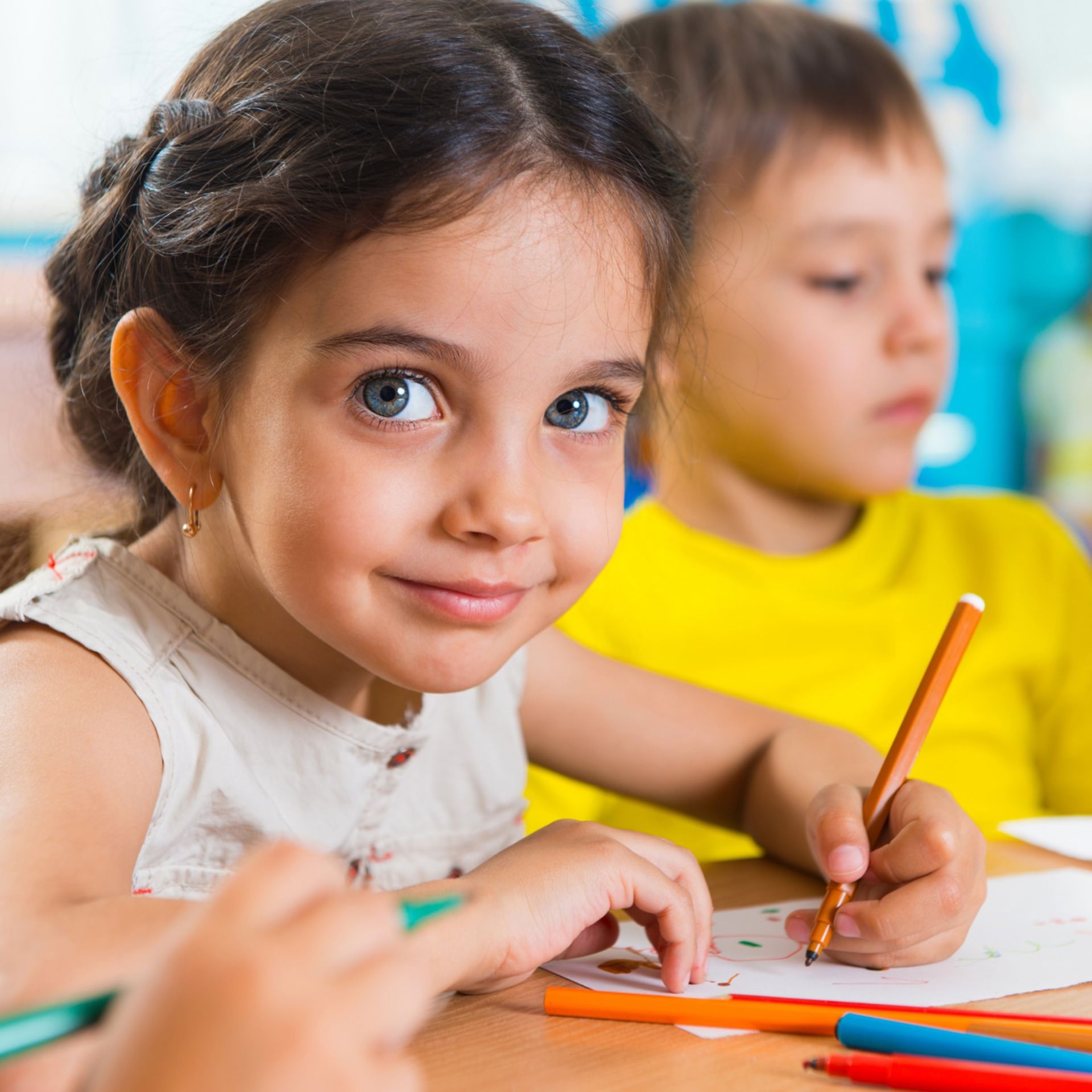 Fille au yeux bleus sourit et dessine en classe